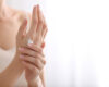 Close-up of hands with a small amount of white cream on the wrist, applying skincare moisturizer