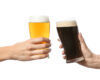 Two hands clinking beer glasses—one pale ale and one dark stout against a white background.