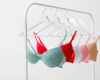 Row of lace bras in pastel colors (mint, red, white, pink, beige) hanging on a white clothing rack.