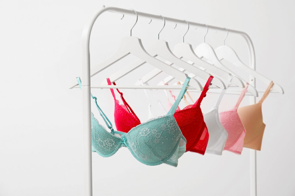 Row of lace bras in pastel colors (mint, red, white, pink, beige) hanging on a white clothing rack.