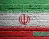 Iran flag painted on a rough brick wall, with green white red stripes and central emblem; 'IRAN' label on a gray badge in the corner.