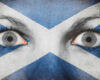 Close-up of a person’s eyes with the Scottish Saltire painted across the face for a bold, patriotic look