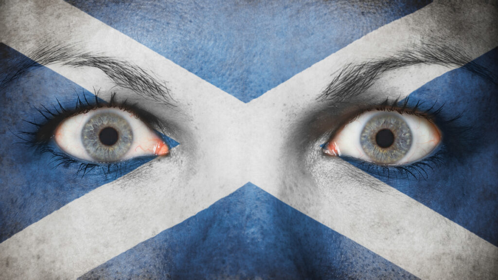 Close-up of a person’s eyes with the Scottish Saltire painted across the face for a bold, patriotic look