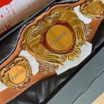 Gold championship belt with an eagle crest, red gem accents, and central plate reading CHAMPION and LONG DRIVE.