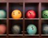 Colorful bowling balls stored in wooden cubbies on metal racks (orange, red, green, teal, pink).