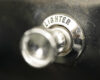 Close-up of a chrome lighter ignition knob labeled 'LIGHTER' on a dark, worn surface.