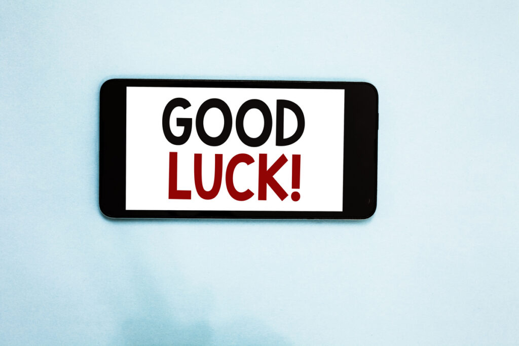 Smartphone displaying the words 'GOOD LUCK!' on a white screen against a light blue background.