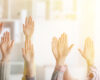 Group of people raising hands in a classroom or meeting, signaling participation.45