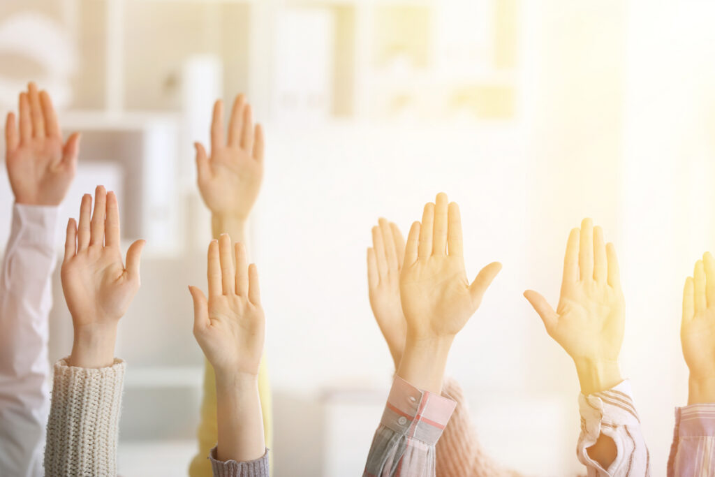 Group of people raising hands in a classroom or meeting, signaling participation.45