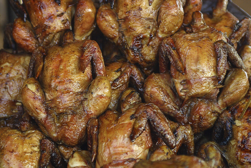 Pile of golden-brown roasted chicken pieces with crispy skin, stacked together.