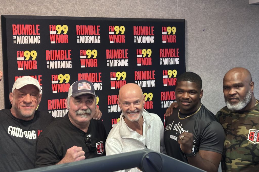 Five men pose for a photo in a radio studio in front of a 'Rumble in the Morning' banner.