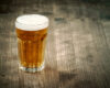 Amber beer in a frothy pint glass on a weathered wooden table