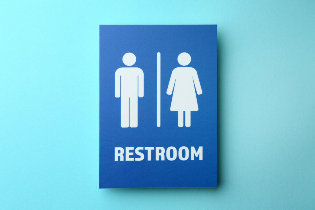 Blue restroom sign featuring male and female icons separated by a vertical divider and the word RESTROOM in white letters on a blue background.